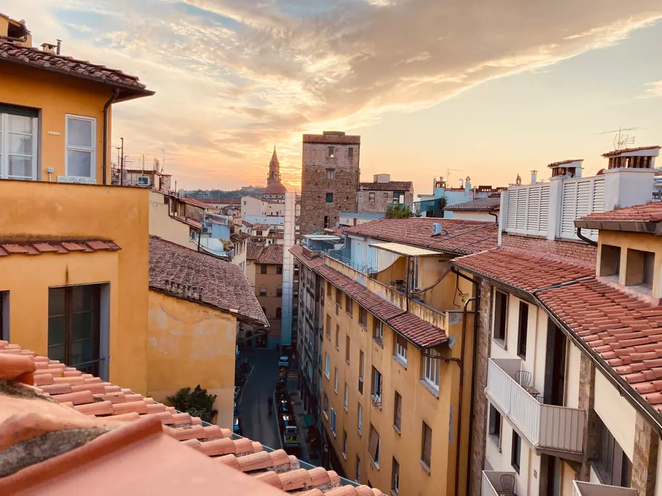Ochre facades and terracotta rooftops above a narrow street at sunset.